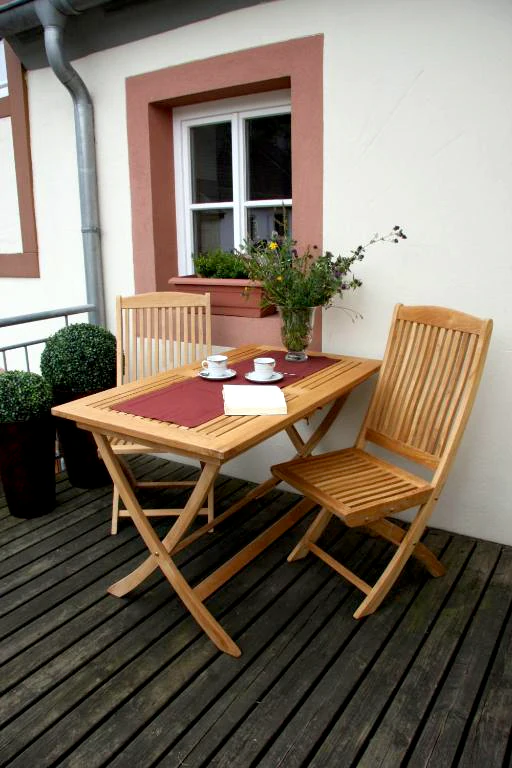 Balkon mit Tisch und 2 Holzstühlen