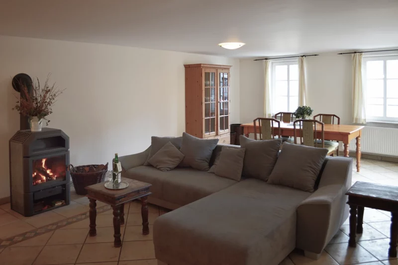 Geräumiges Zimmer mit brennendem Specksteinofen, bequemer Eck-Couch und Esstisch